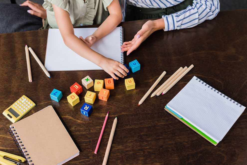 papel dos brinquedos pedagógicos criança brincando em uma mesa de madeira da cozinha junto de seus pais em um dia ensolarado