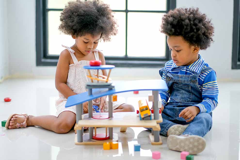 brinquedo pedagógico gera autonomia duas crianças brincando com brinquedos pedagógicos no chão de uma sala de estar em um dia ensolarado
