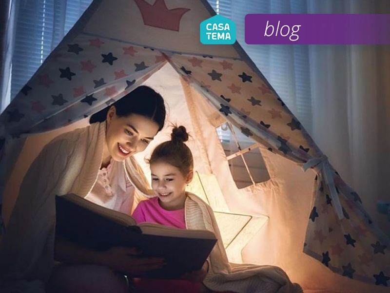 Mamãe e filha lendo histórias infantis na tenda infantil