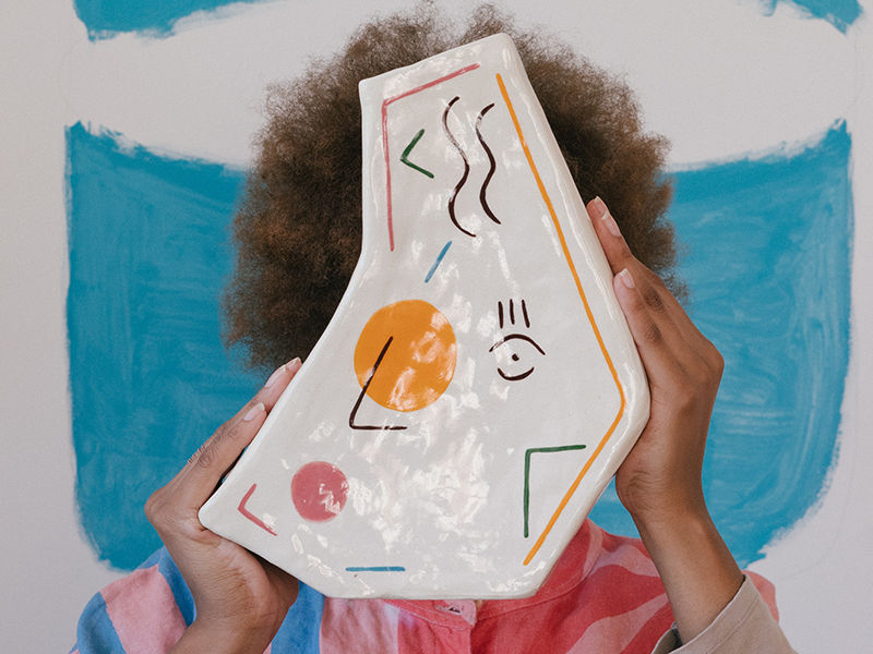 uma criança segurando uma pintura feita em um prato de porcelana
