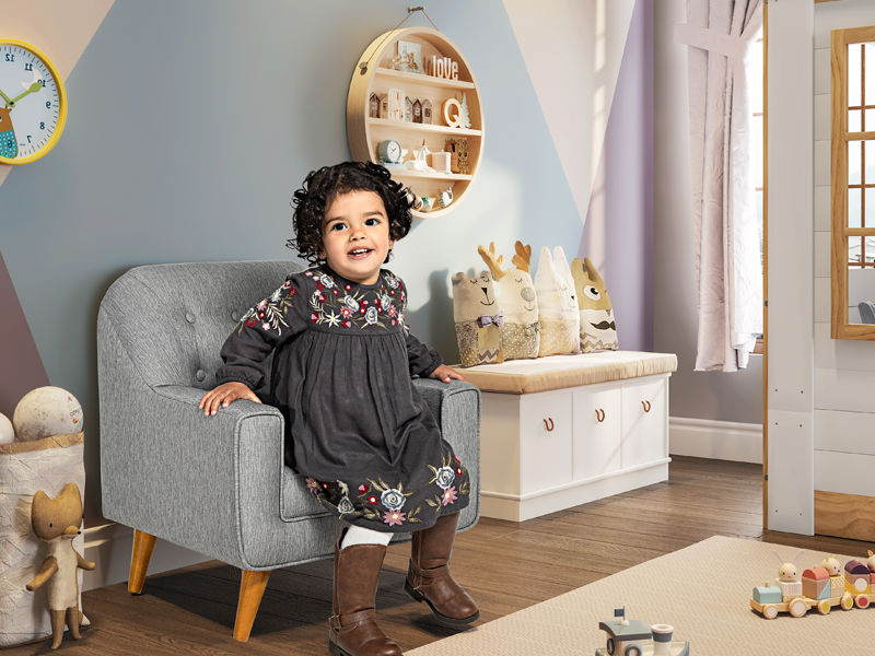 menina sentada em uma poltrona em um quarto infantil