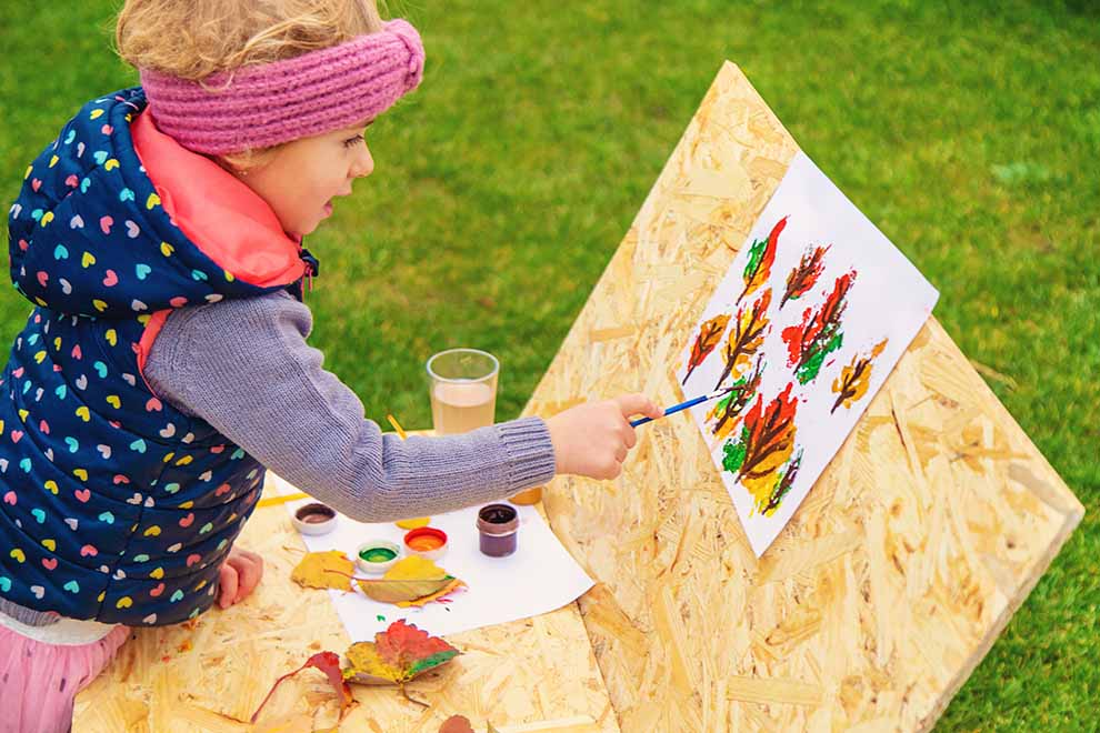 criança pintando ao ar livre em um dia de outono