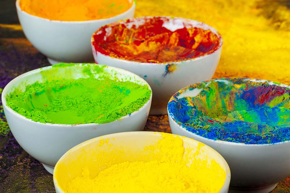 várias tigelas com tinta de farinha com corante de várias cores em cima de uma mesa de madeira 