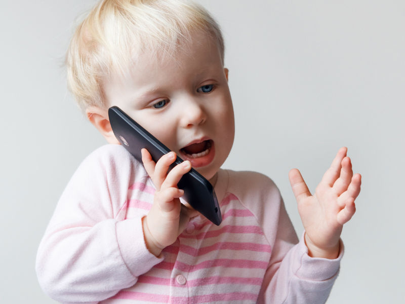 criança com um telefone na mão enquanto fala com alguém por ligação