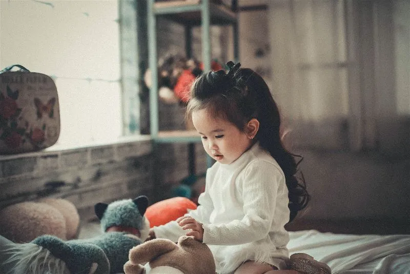 criança menina brincando com brinquedos de pelúcia 