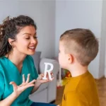 Mulher explicando como pronunciar a letra R a um menino