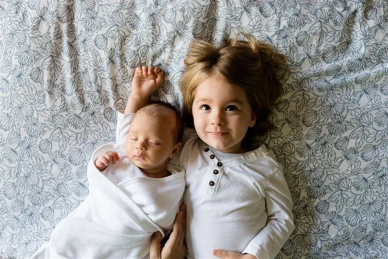 dois bebês abraçados deitados de barriga para cima 