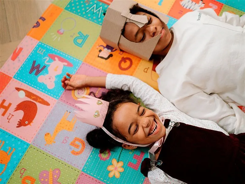 Menino e menina deitados num tapete colorido brincando