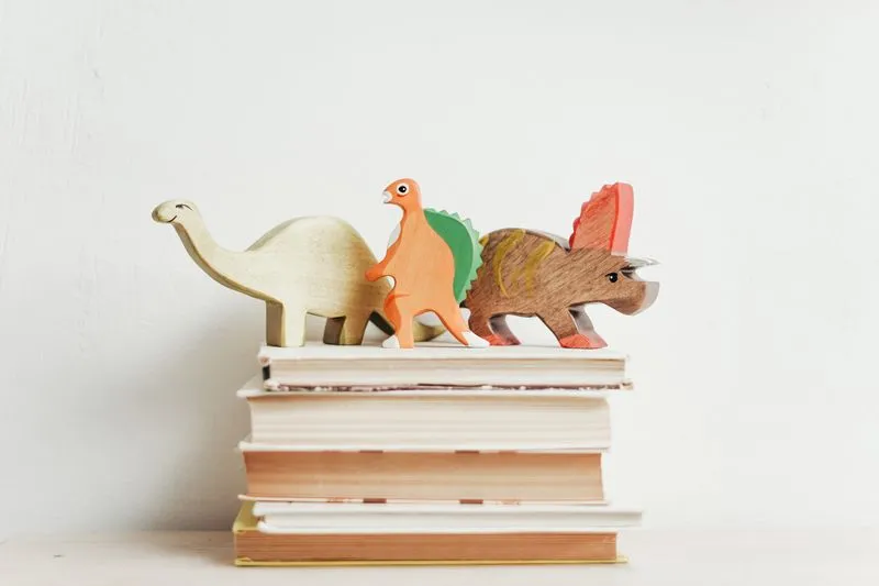 livros empilhados com brinquedos de dinossauro