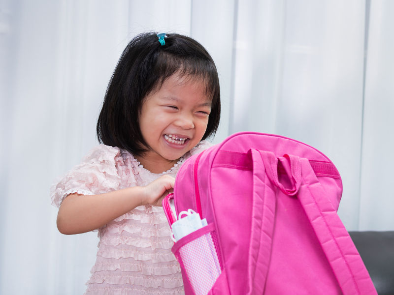 menina pequena arrumando a mochila para a escola