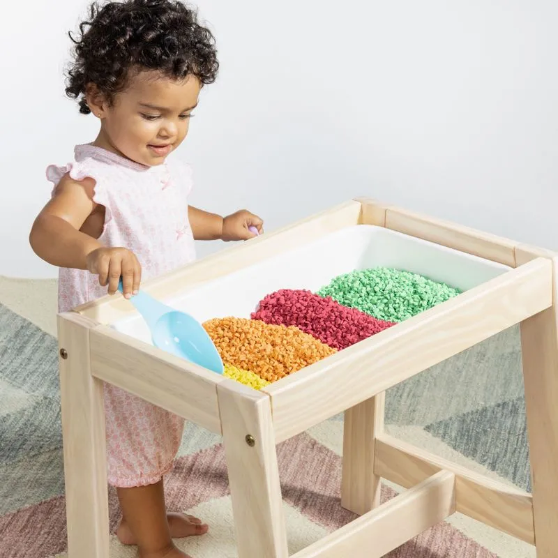 menina brinca com uma mesa criativa cheia de pedrinhas coloridas