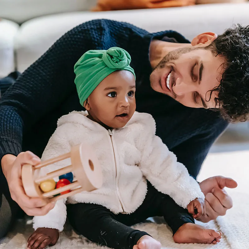 pai e filha bebê sorrindo e brincando com um brinquedo montessoriano
