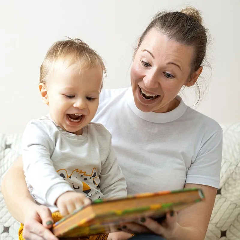mãe e bebê brincam com um livro colorido