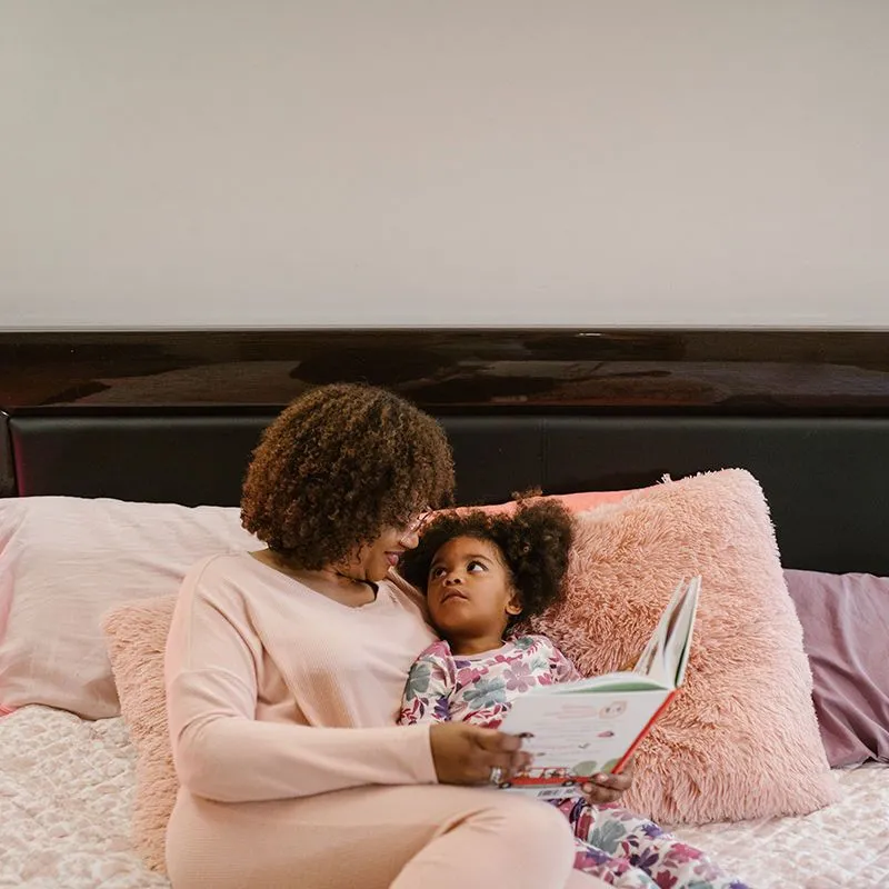 mãe e filha leem um livro juntas na cama 