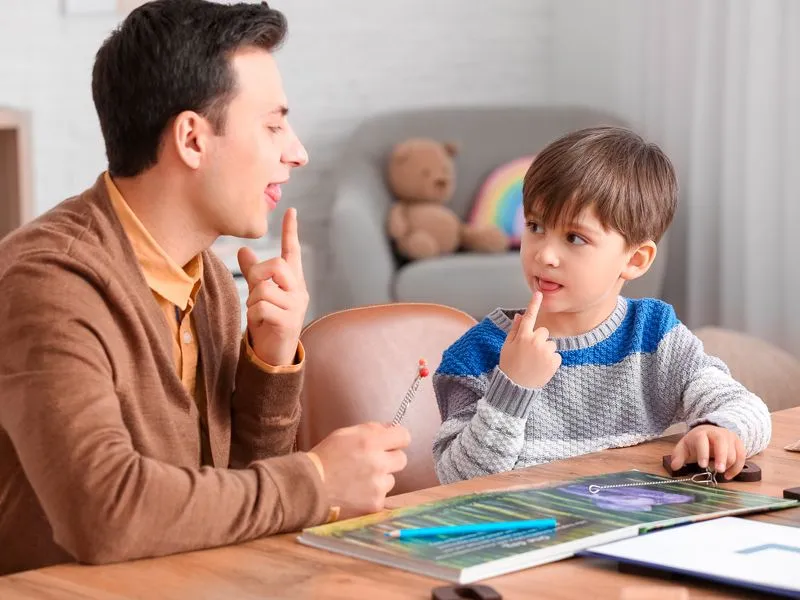 pai e filho apontam para as suas línguas enquanto estudam a pronúncia de palavras