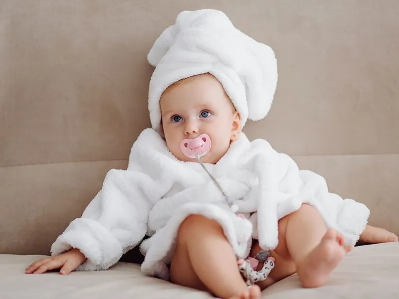 bebê embrulhada em uma toalha com chupeta na boca