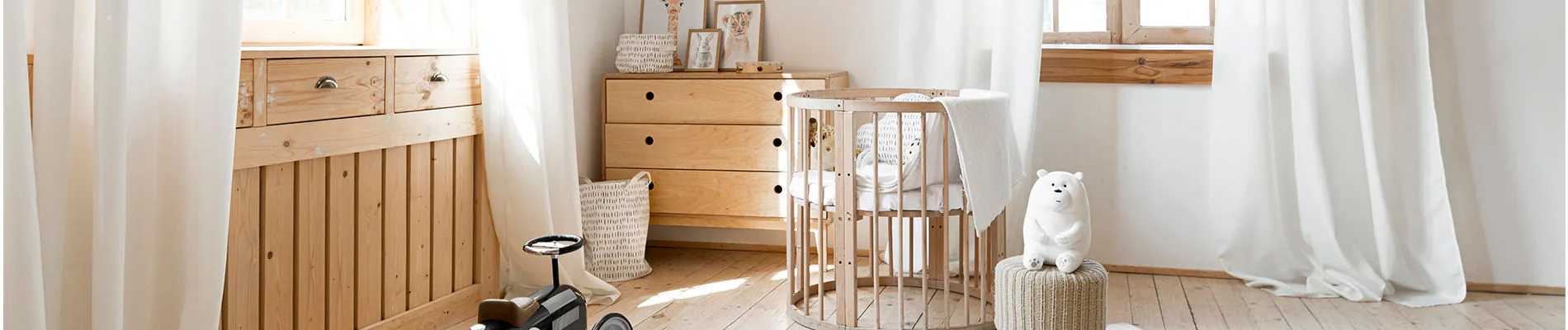 Quarto de bebê com móveis em madeira natural. Na foto há uma cômoda e um berço.
