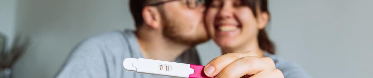 casal feliz com um teste de gravidez positivo