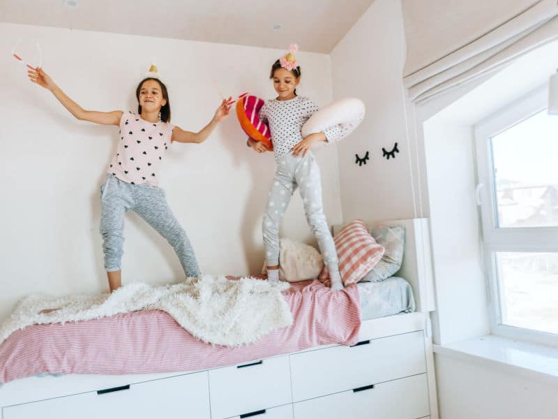 duas meninas em cima da cama dançando e pulando
