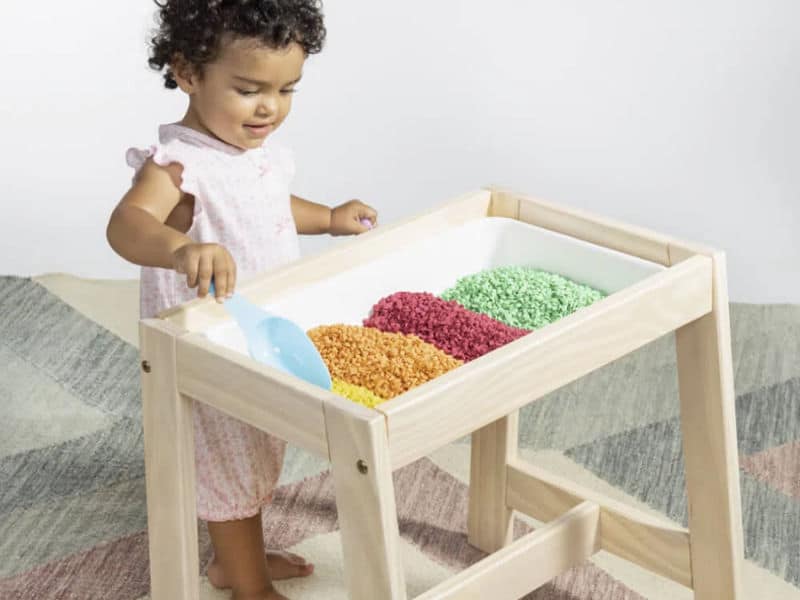 menina de dois anos brincando de exploração com caixas Montessori para descobrir novas sensações