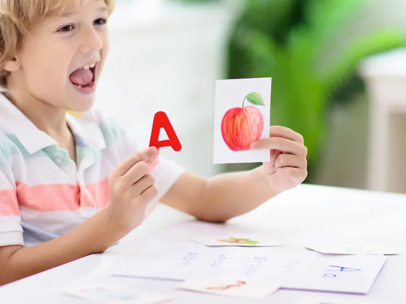 menino aprendendo vogais por meio dos desenhos