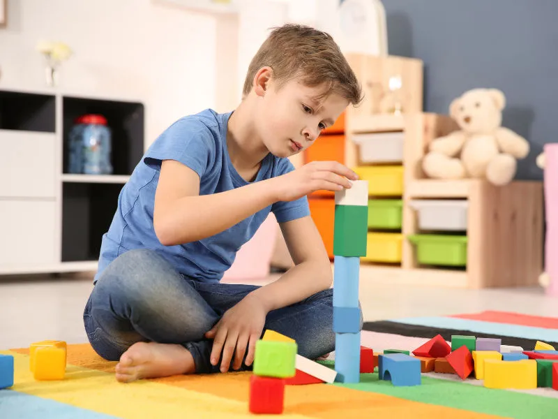 menino pequeno de 7 anos brincando com bloco de montar