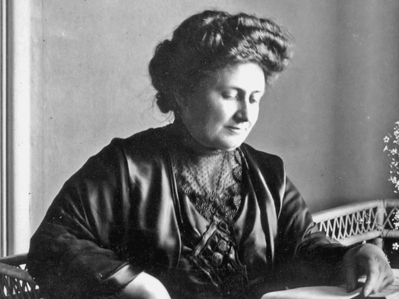 Maria Montessori sentada em uma cadeira