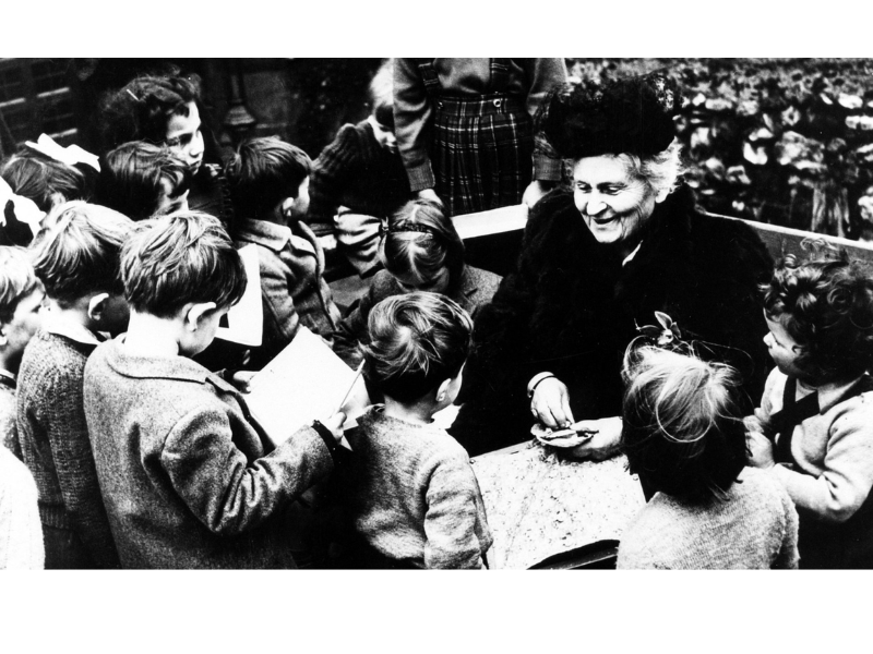 Maria Montessori com várias crianças em volta