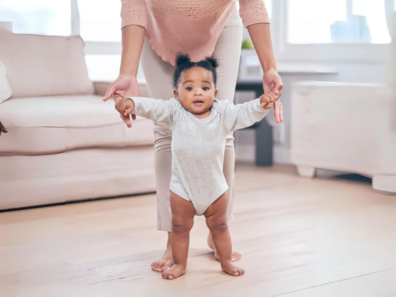 mãe ensinando garotinha de um ano a andar sozinha