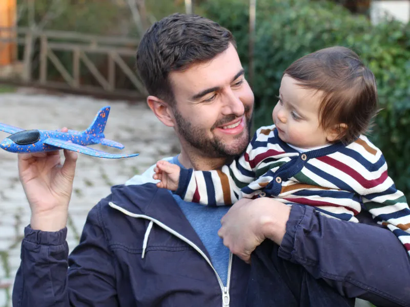 pai brincando com de aviãozinho com bebê de um ano