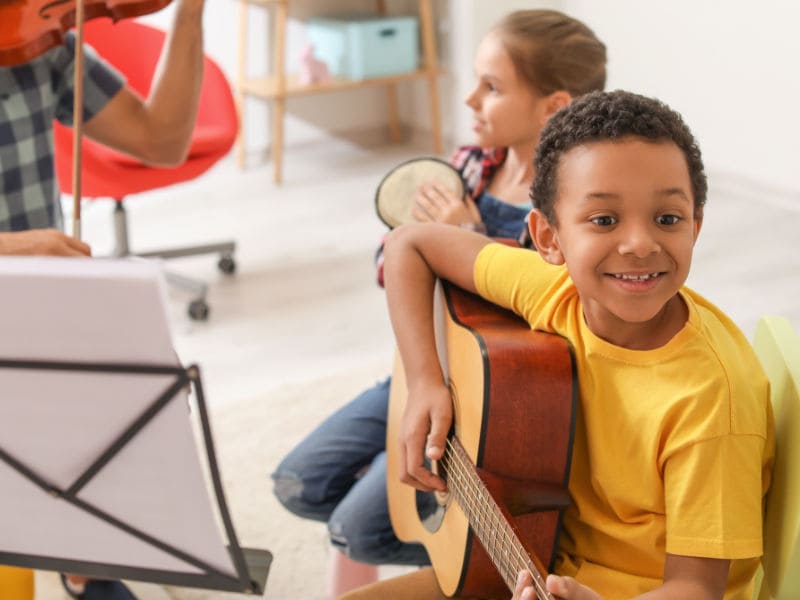 menino de 5 anos aprendendo a tocar violão para melhorar a coordenação motora