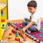 Criança brincando com brinquedos de madeira coloridos.