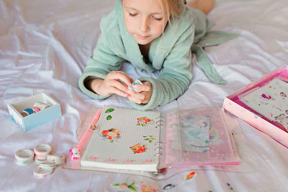 Criança colando adesivos em caderno colorido