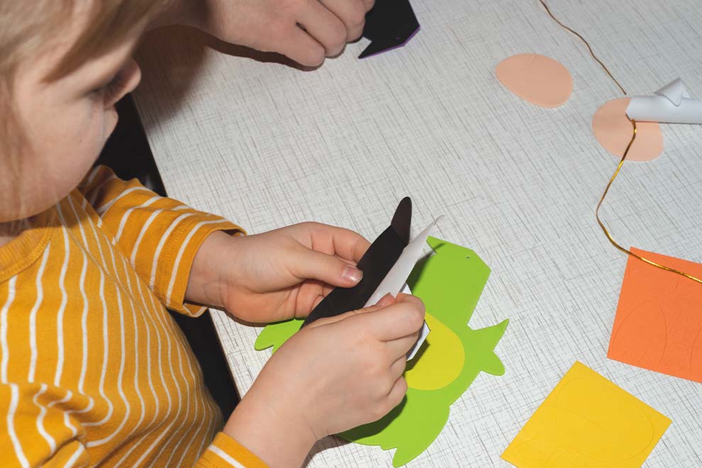 Criança recortando papel colorido em atividade de artesanato.