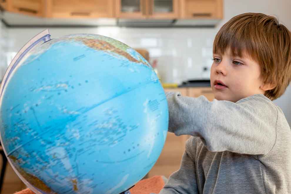 Criança explorando um globo terrestre em casa
