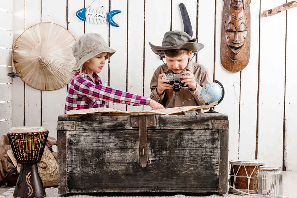 Crianças explorando mapa em baú de aventuras