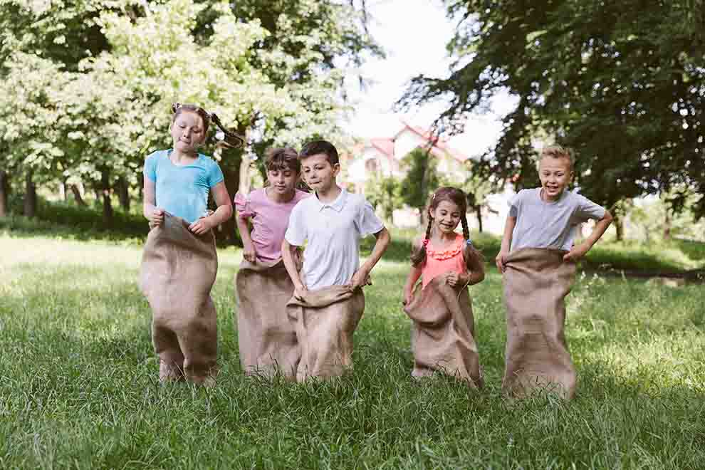 Crianças brincando de corrida em sacos no campo