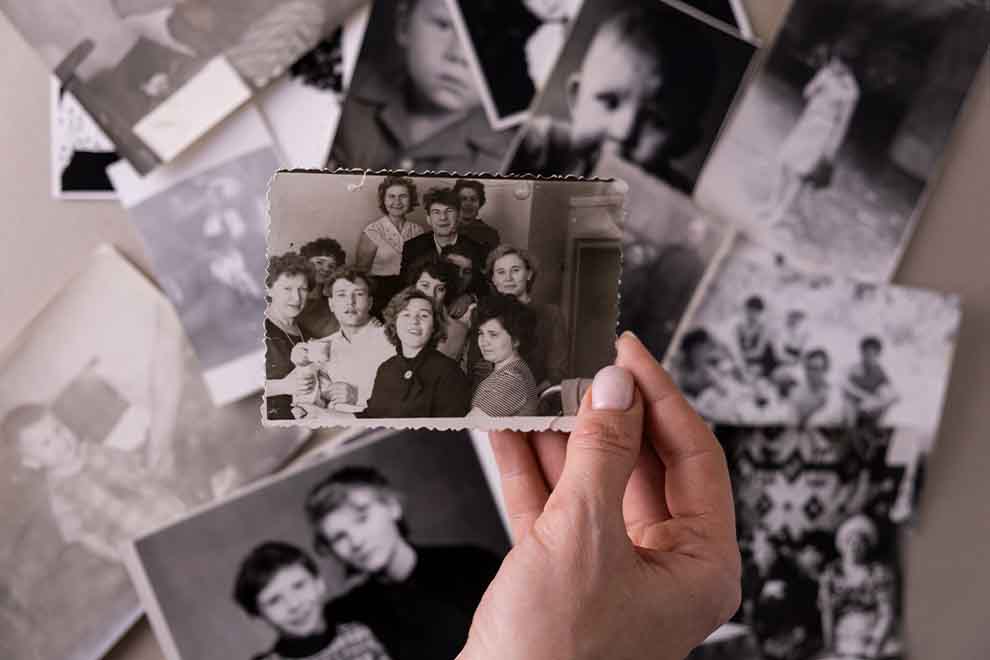 Mão segurando foto antiga entre outras fotos.