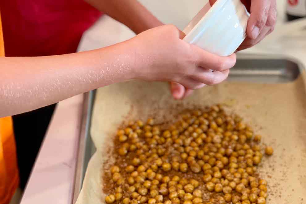 Mãos temperando grão-de-bico antes de assar