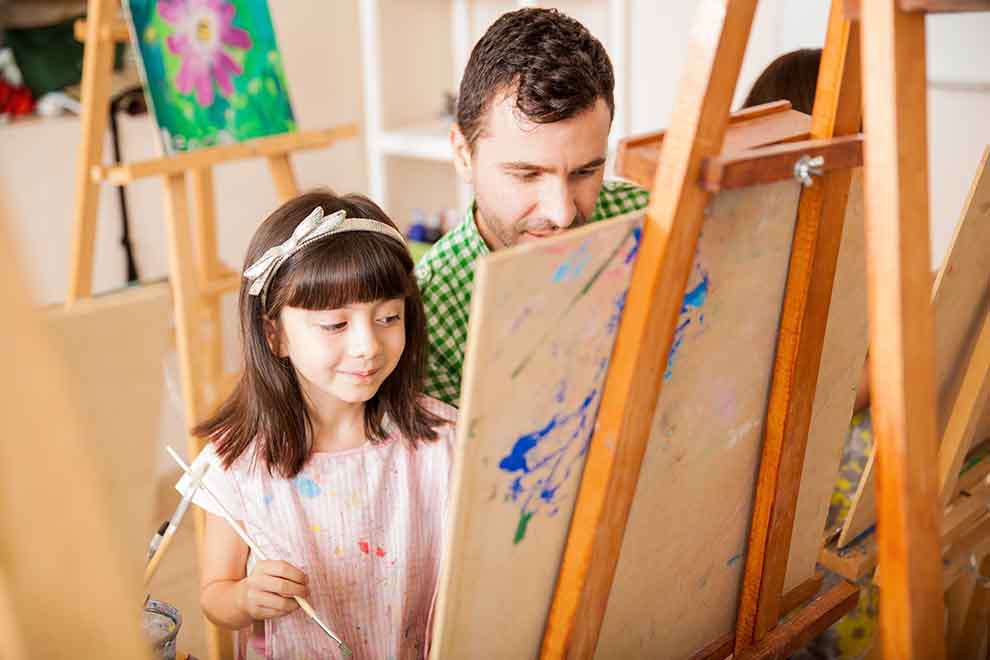Pai e filha pintando em um estúdio de arte.