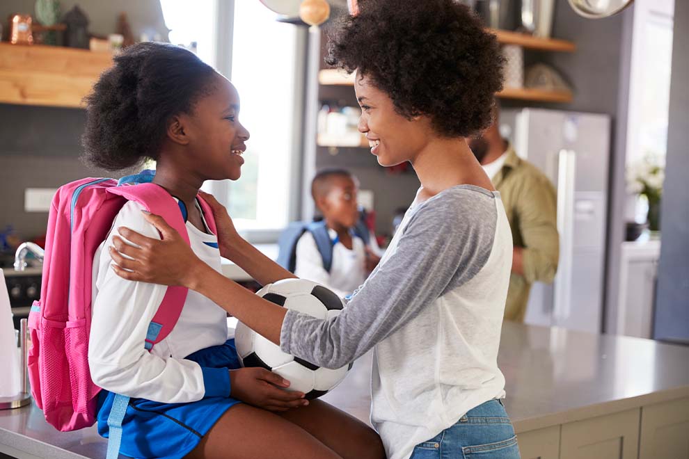 Mãe e filha sorrindo com bola de futebol